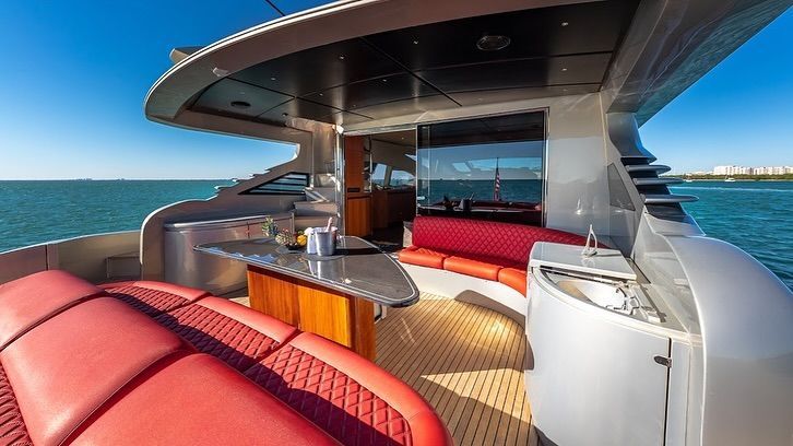 The inside of a yacht with red seats and a table in the water.