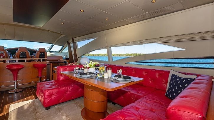 A living room on a boat with red couches and a table.