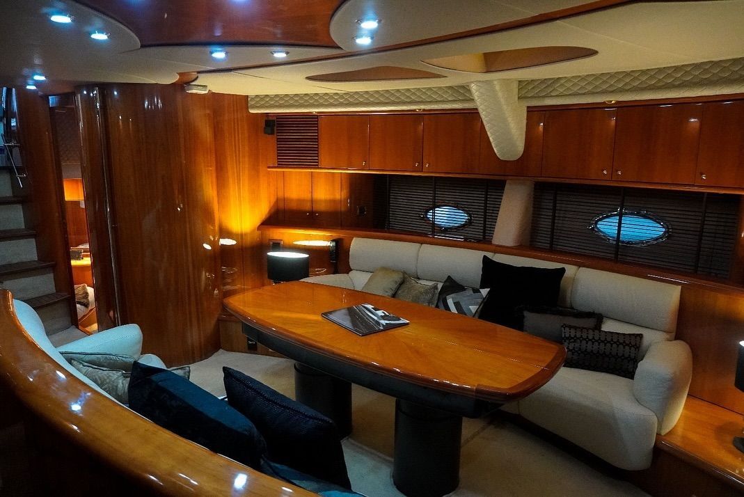 A living room on a boat with a couch , table and chairs.