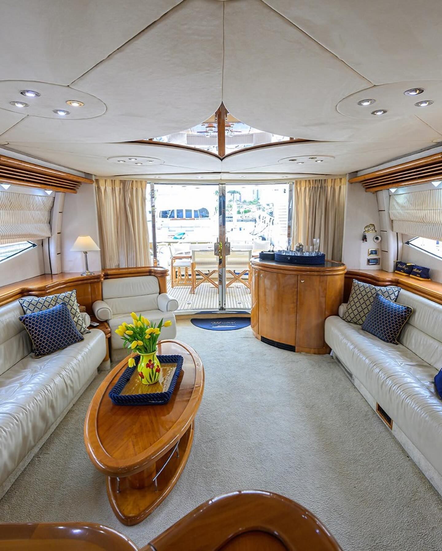 A living room on a boat with white couches and a wooden table