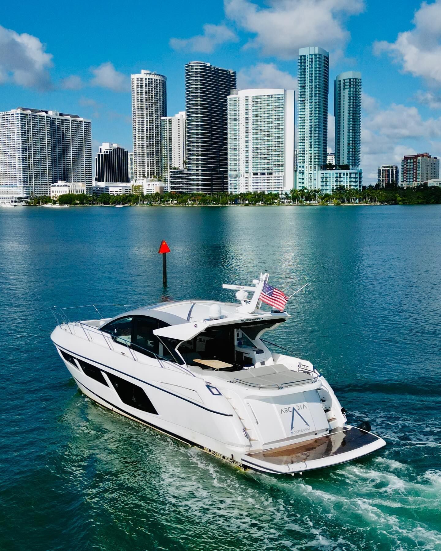 A white boat is floating on a body of water with a city skyline in the background.