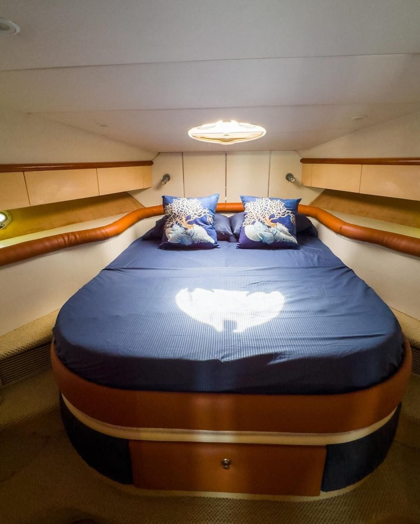 A bed on a boat with blue sheets and pillows