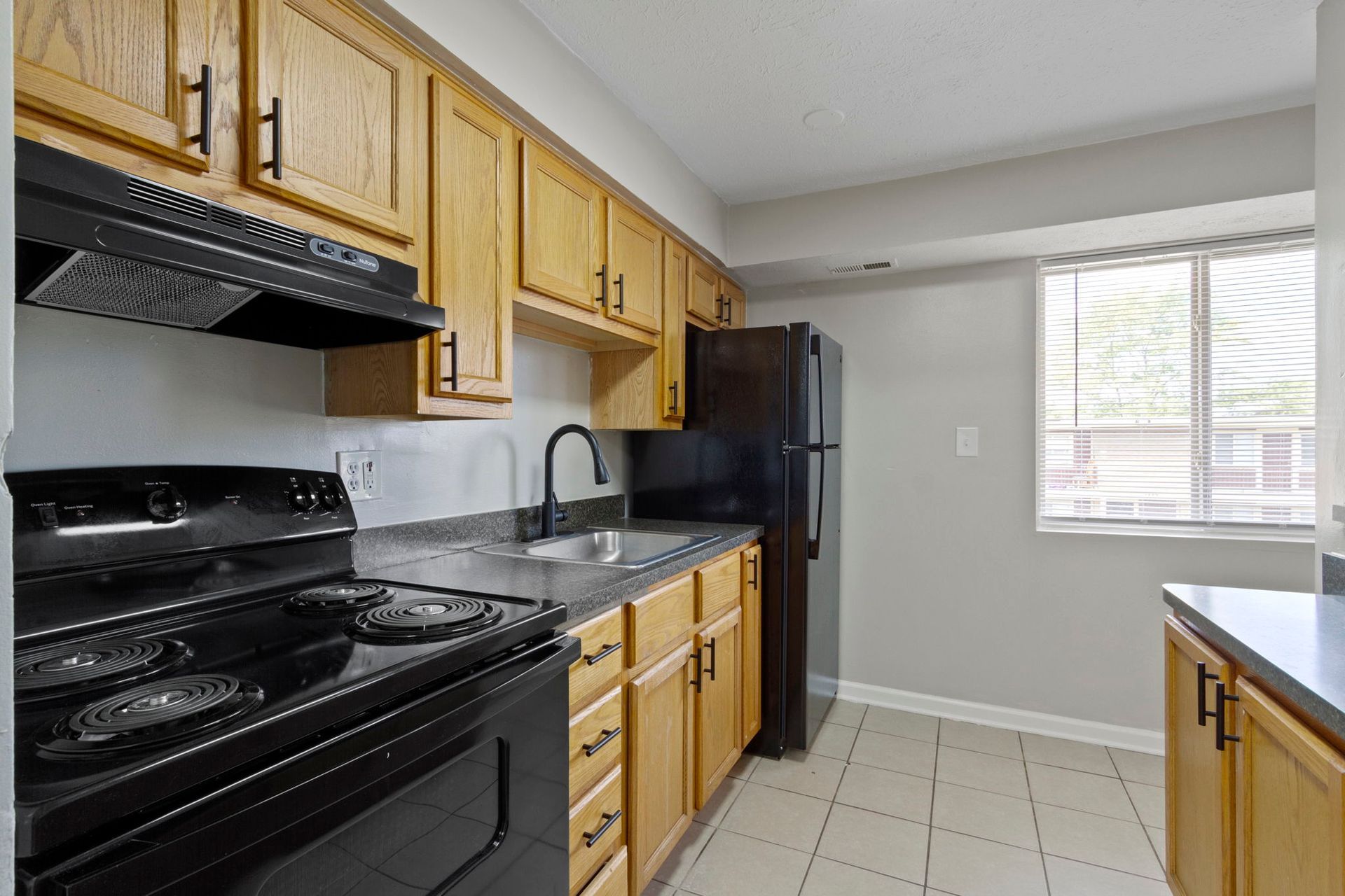 Kitchen with wooden cabinets, black appliances, and a window.
