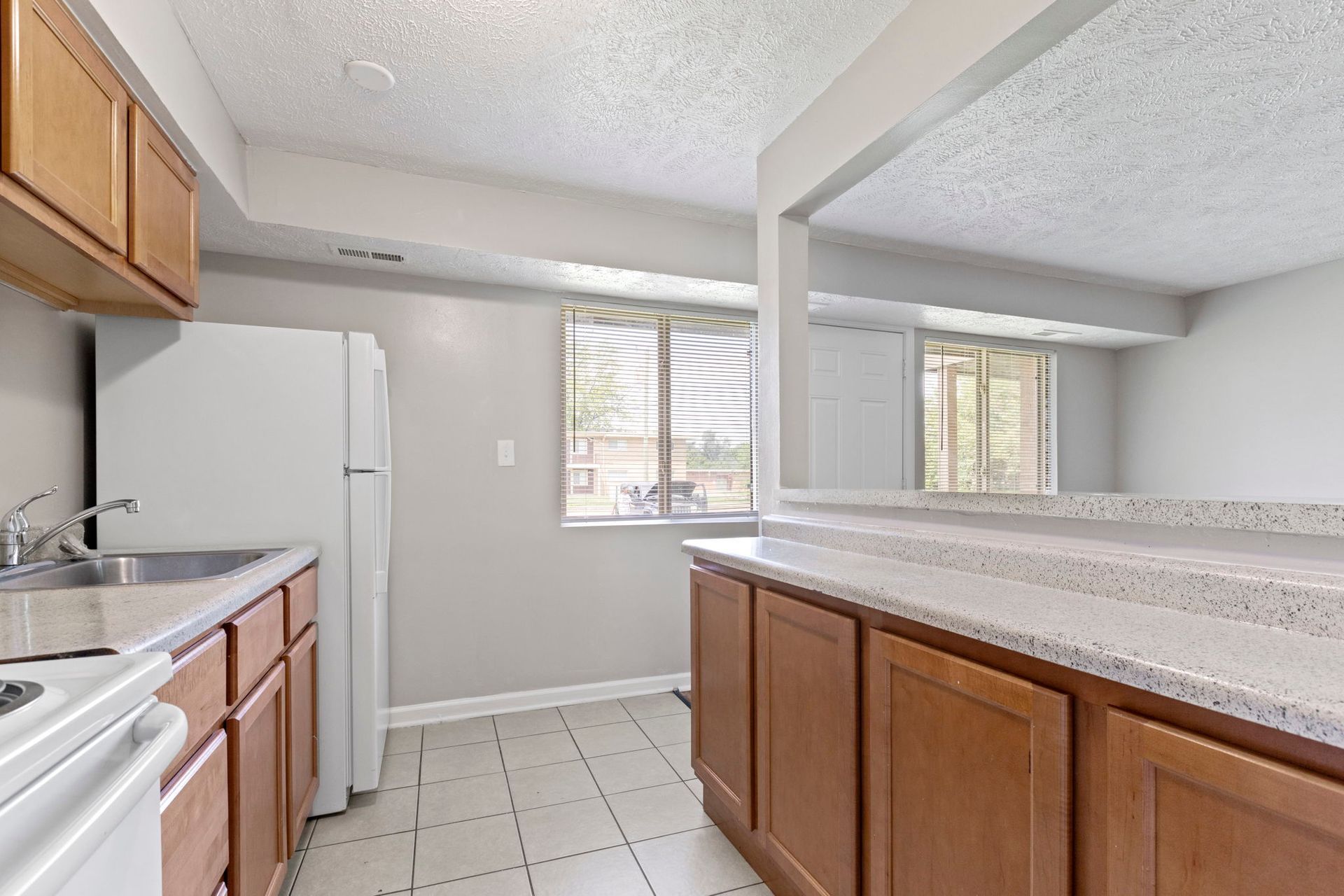 Kitchen with brown cabinets, white appliances, and light countertops. A window provides natural light.
