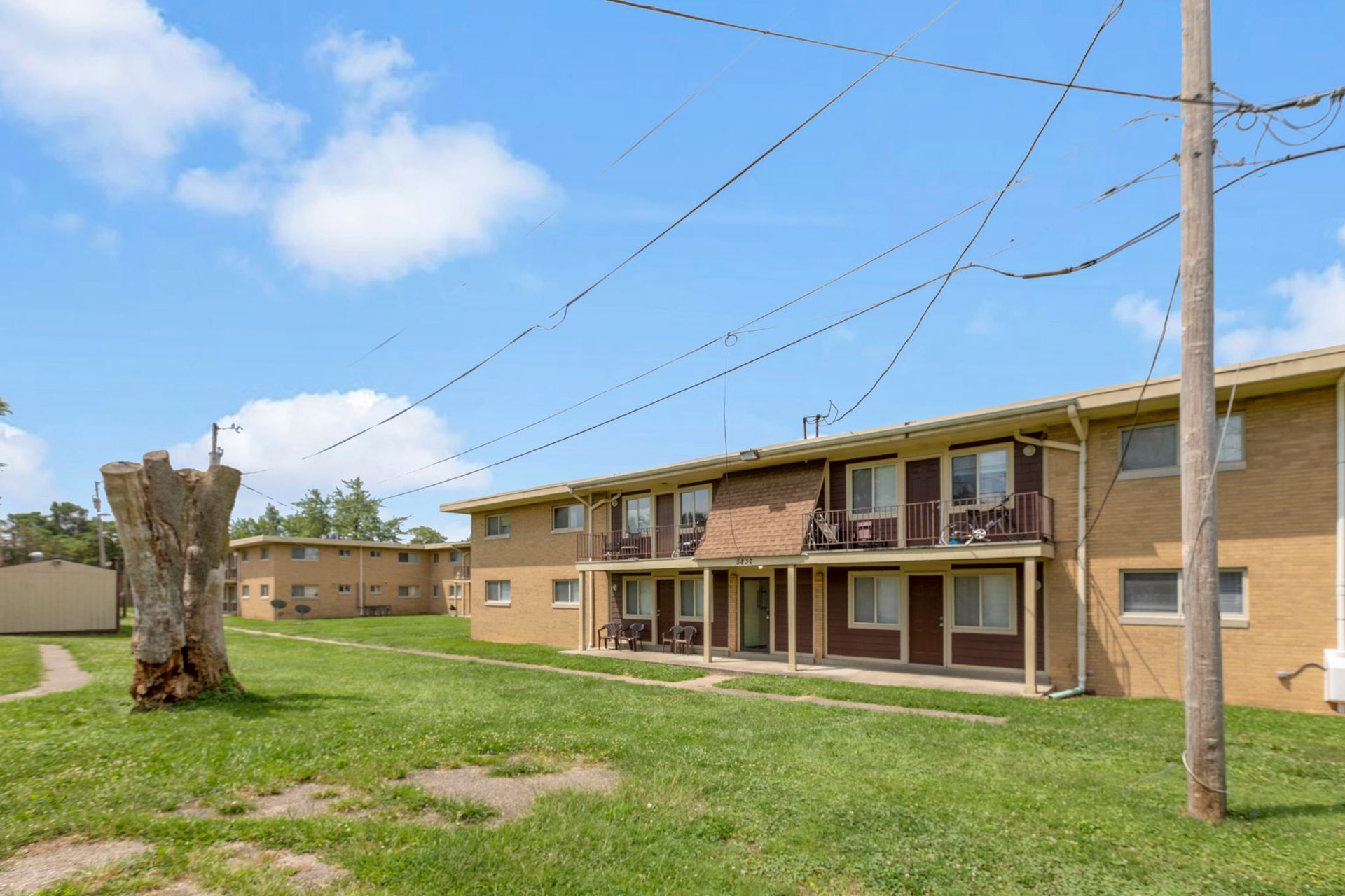 Apartment buildings with brown trim and balconies under a blue sky with power lines.