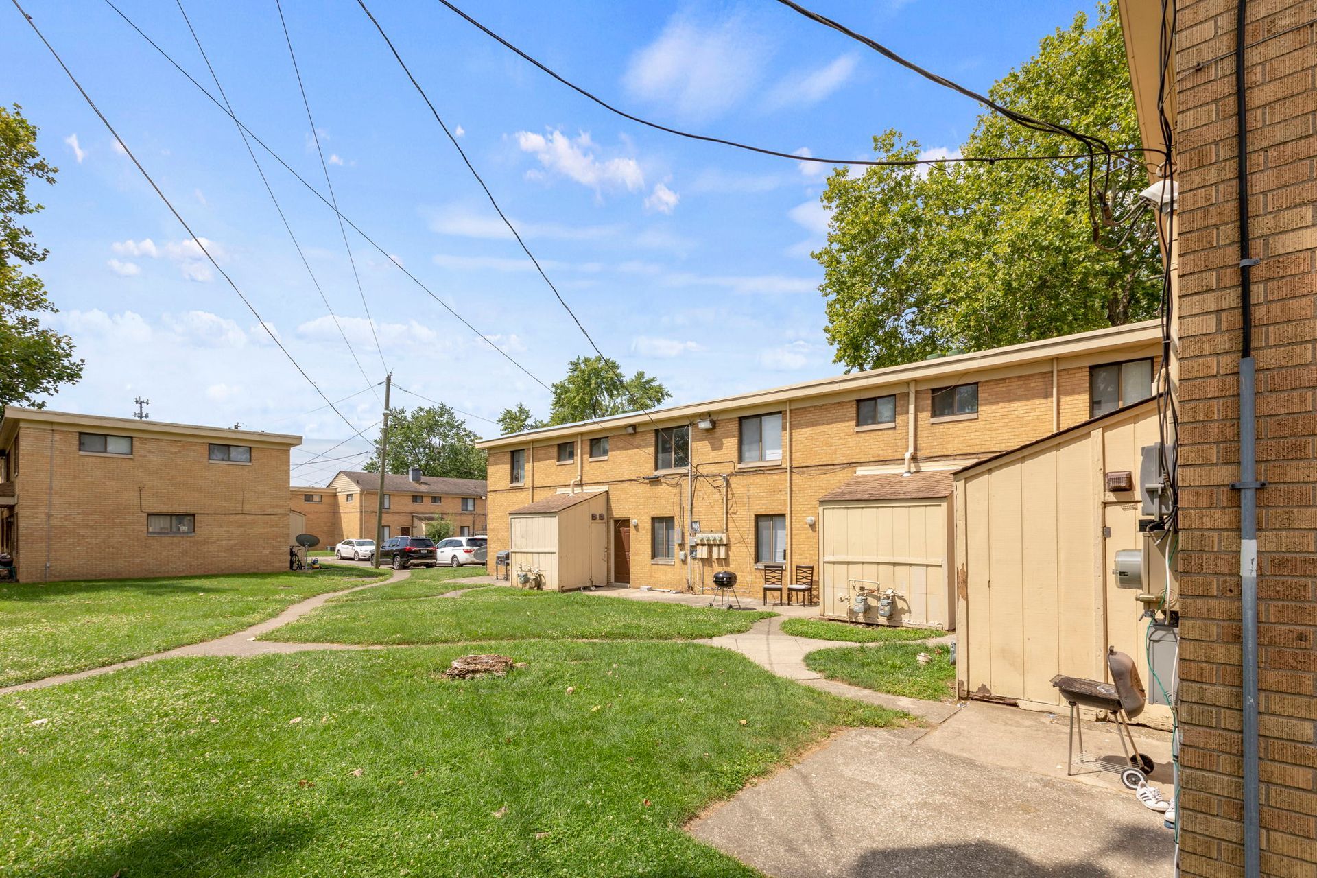 Apartment buildings with brick exteriors and green lawns. Power lines overhead.