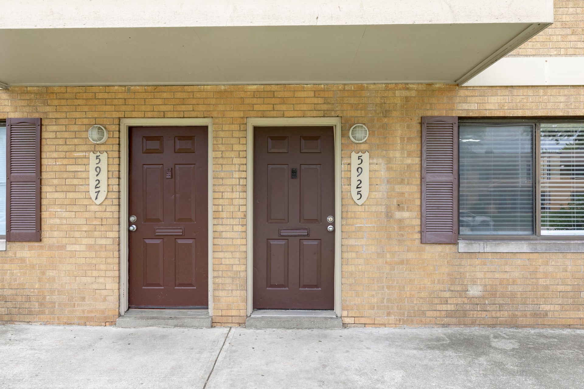 Two brown doors on a tan brick building. The doors have unit numbers: 5921 and 5925.