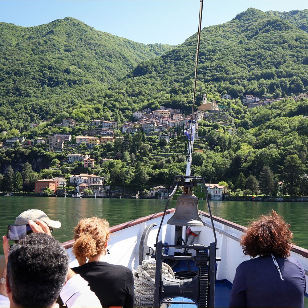 Small ship with people and view of the Alps on Lake Como  located in the Lombardy region