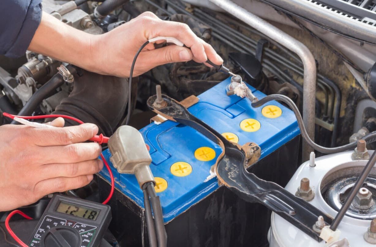 A Person Is Testing A Car Battery With A Multimeter.