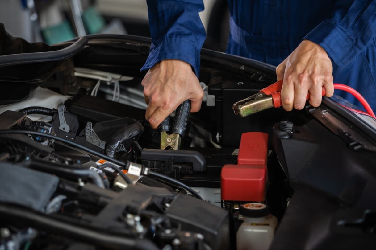 A Man Is Charging A Car Battery With A Jump Starter — Brad's Auto Electrical in Mareeba, QLD