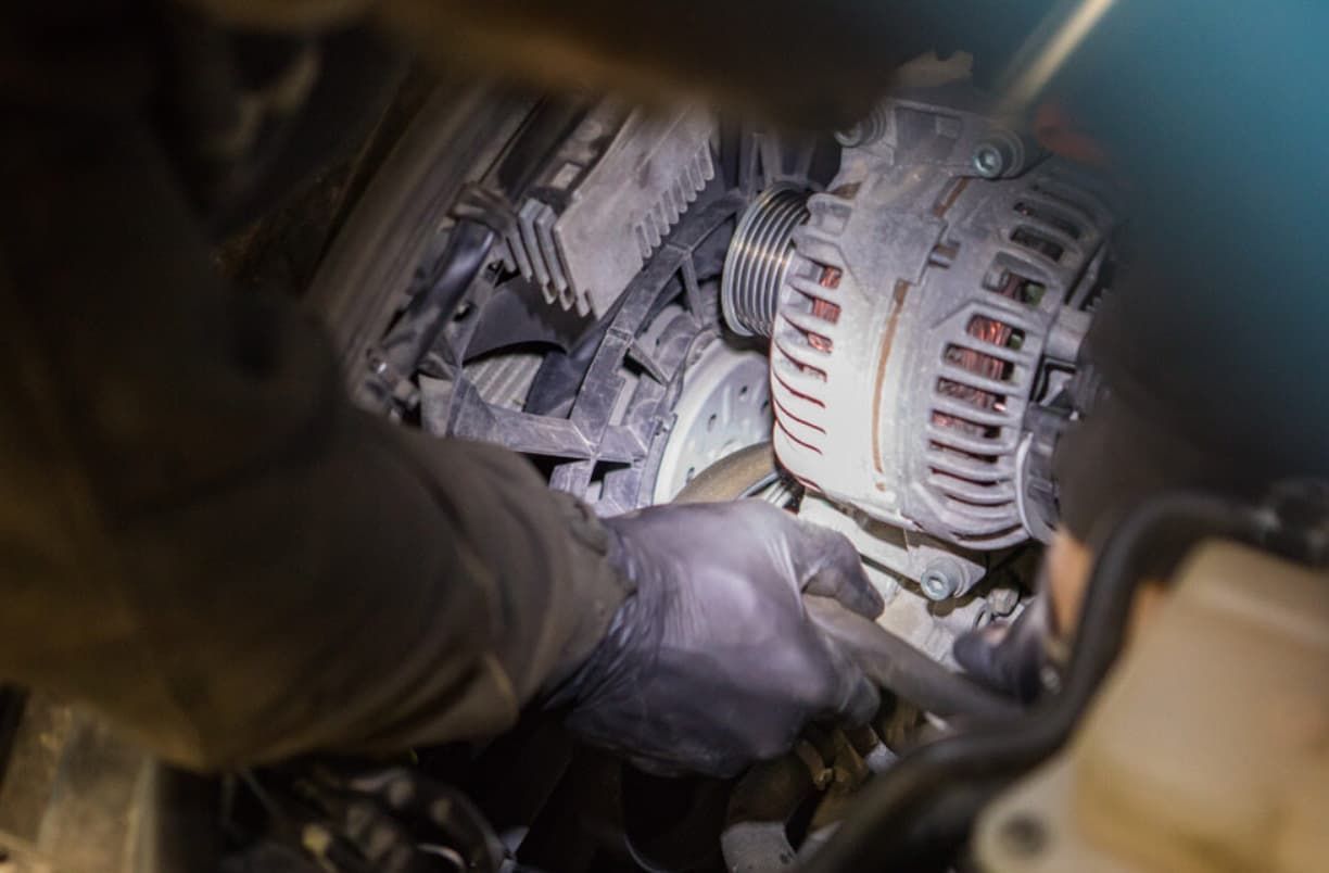 A Person Is Working On A Car Engine With A Flashlight — Brad's Auto Electrical in Mareeba, QLD