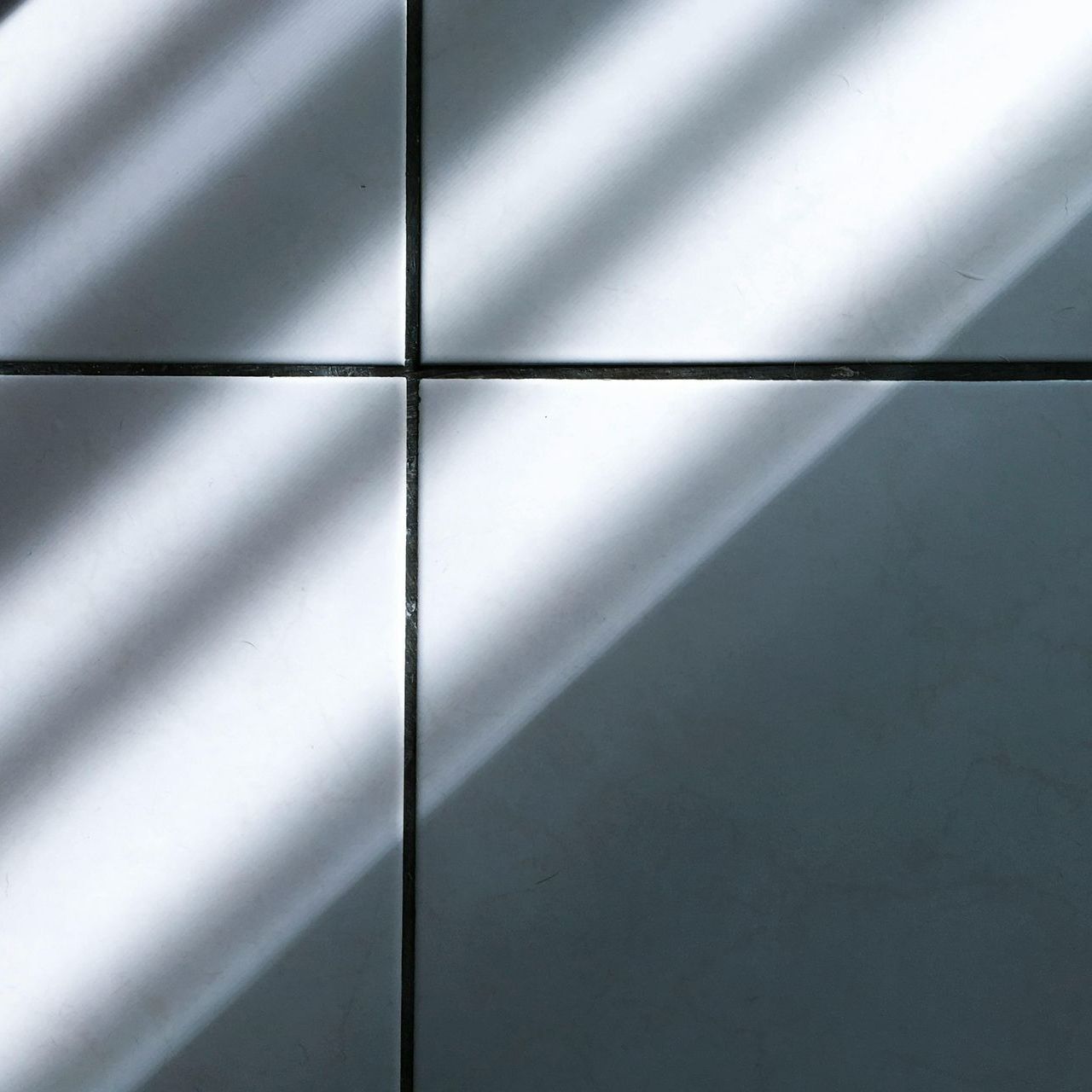 A close up of a tiled wall with a shadow on it