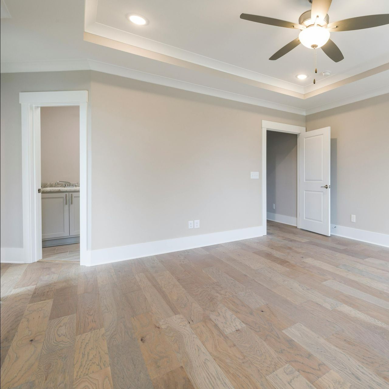 An empty room with hardwood floors and a ceiling fan