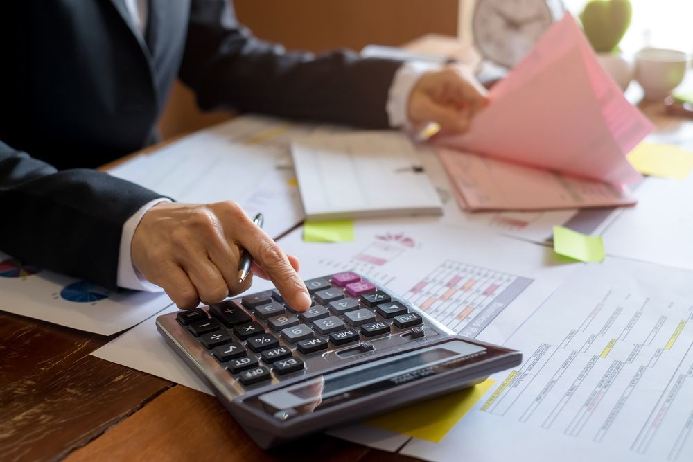 A Person Using a Calculator, Reviewing Paperwork on a Desk — Careful Books in Tablelands, QLD