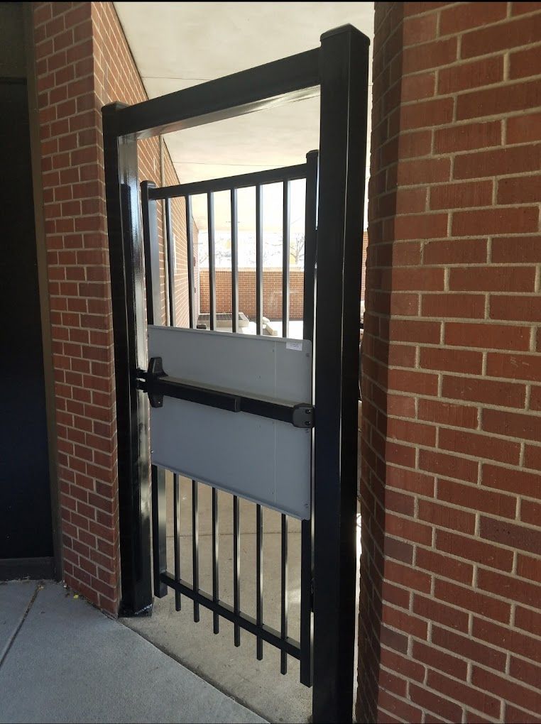A black gate is open to a brick building