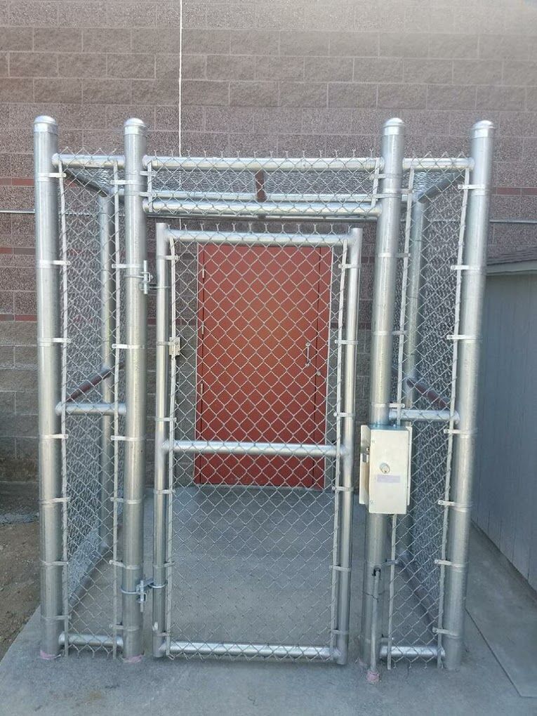 A chain link fence with a red door behind it