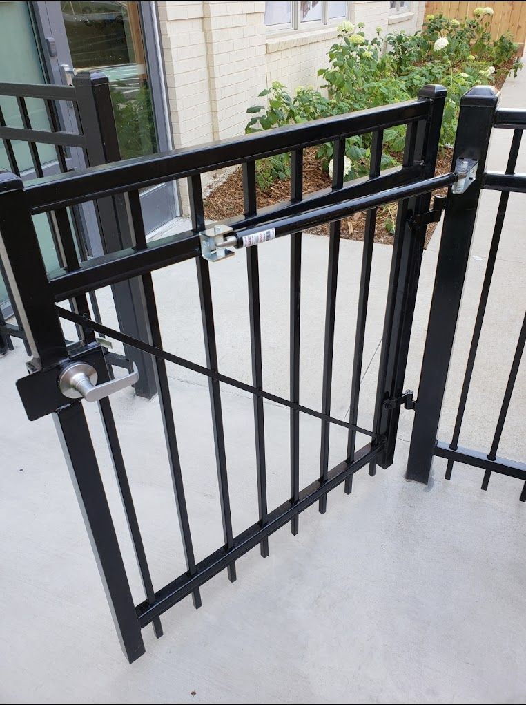 A black metal gate is open to a concrete walkway