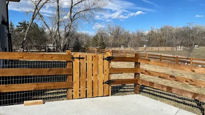 A wooden fence with a gate in the middle of a yard.