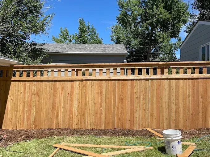 A wooden fence is being built in the backyard of a house.