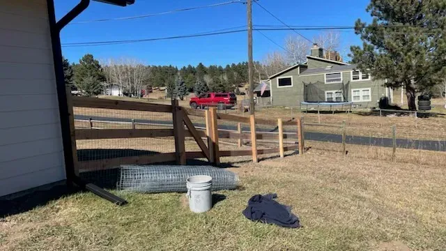 A wooden fence is being built in the backyard of a house.