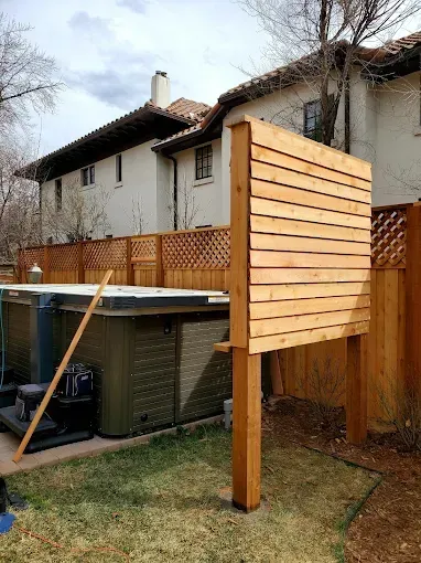 A wooden fence is being built in the backyard of a house.