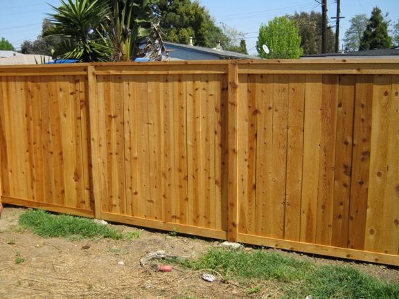 A wooden fence is sitting in the grass in front of a house.