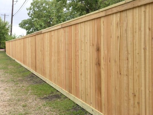 A long wooden fence is sitting in the middle of a grassy field.