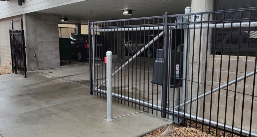 A black metal fence is surrounding a parking garage.