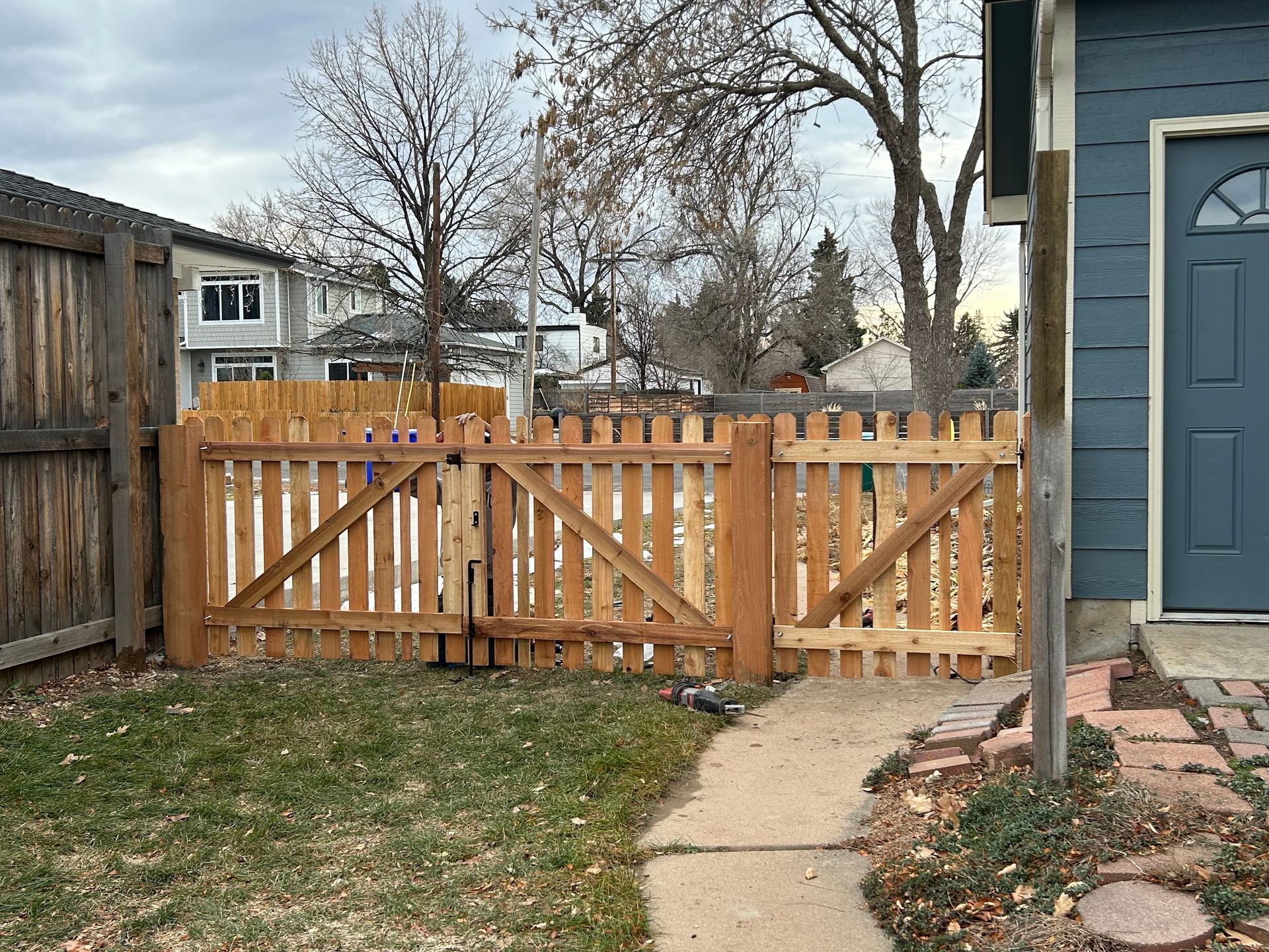Wooden picket fence with two gates in front of a house.