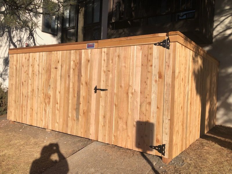 A wooden fence with a door is in front of a house.