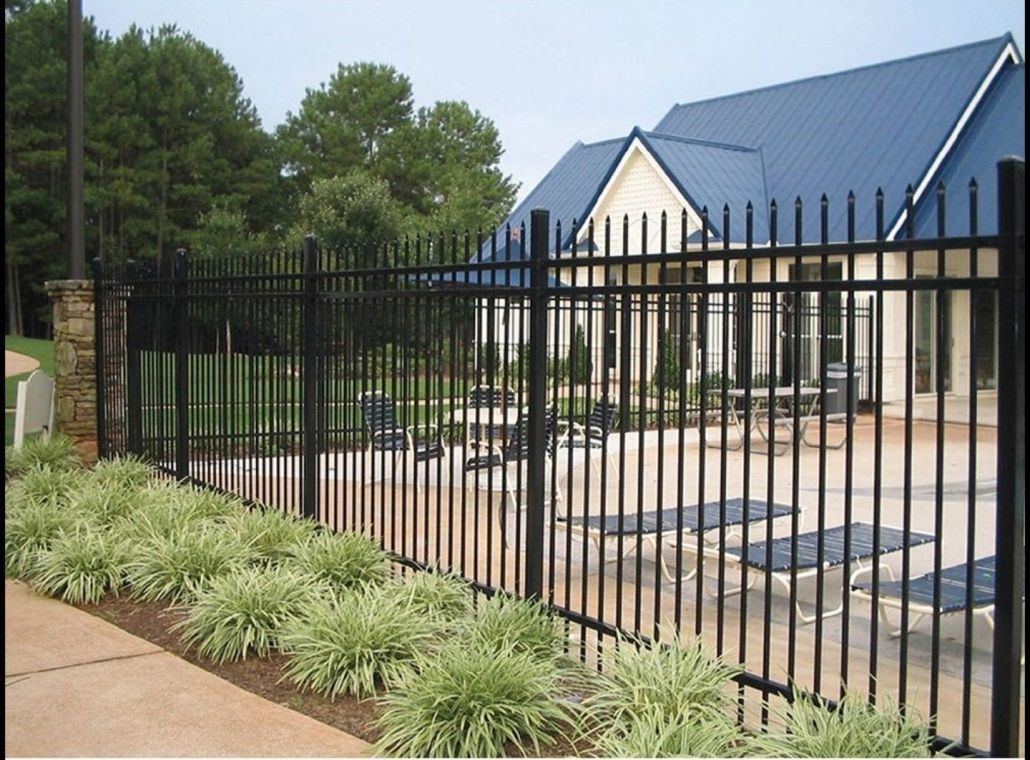 A black fence surrounds a house with a blue roof