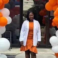 A woman wearing a white lab coat with a crest on it