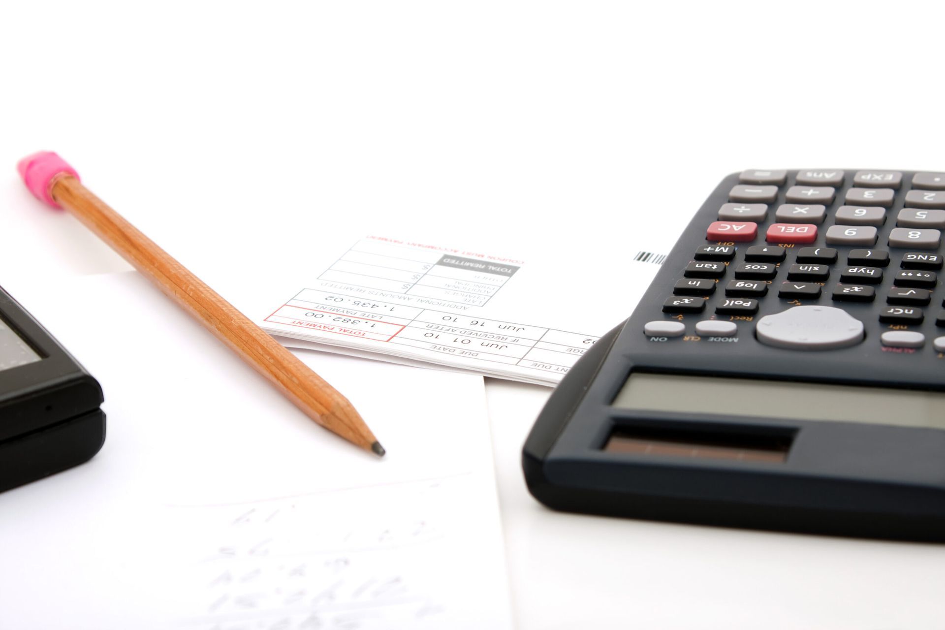 A calculator sits on a table next to a pencil