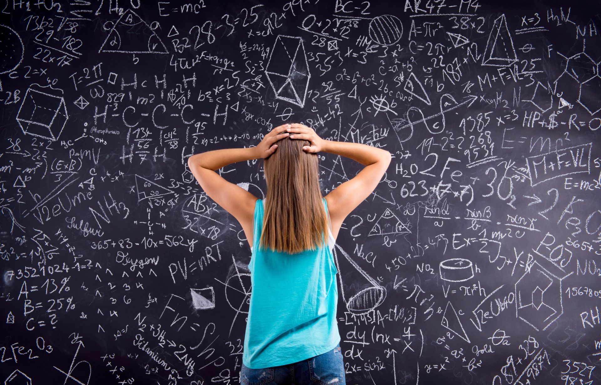 A woman is standing in front of a blackboard full of math equations