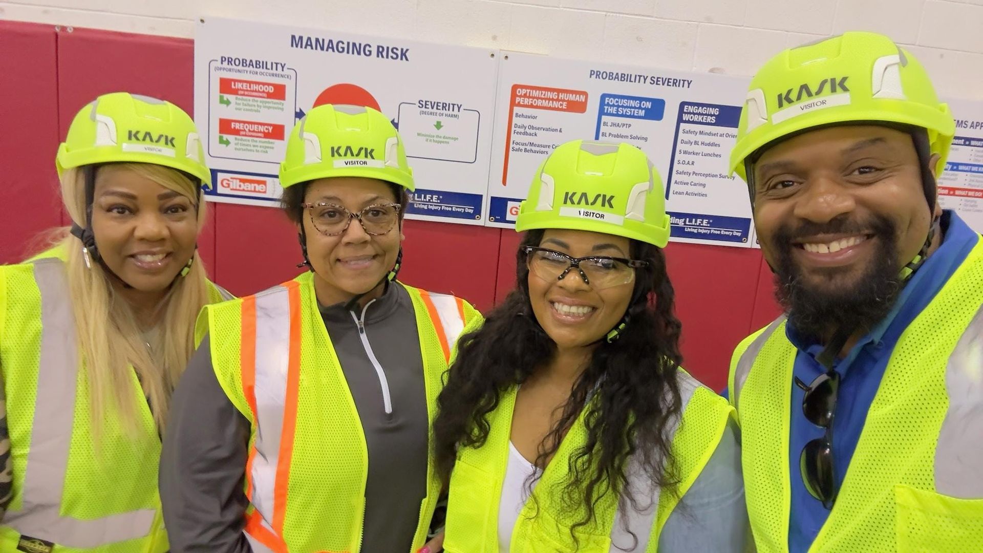 A group of people wearing hard hats and safety vests are posing for a picture.
