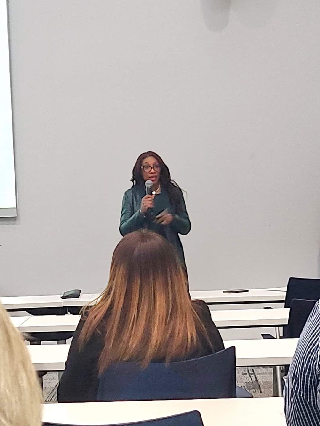 A woman is giving a presentation to a group of people in a classroom.