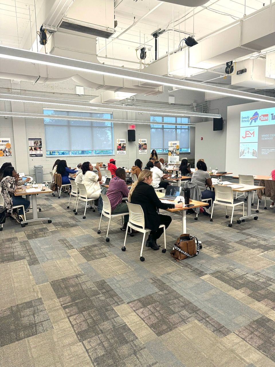 A group of people are sitting at tables in a large room.