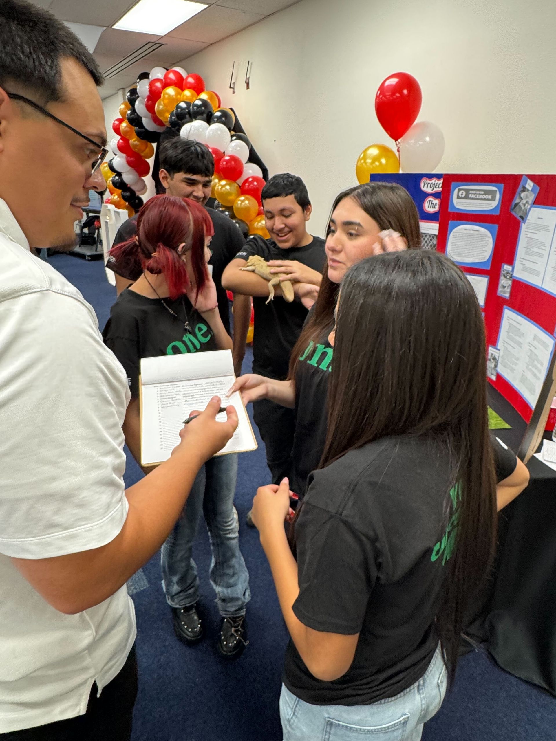 A group of people are standing in a room with balloons in the background.