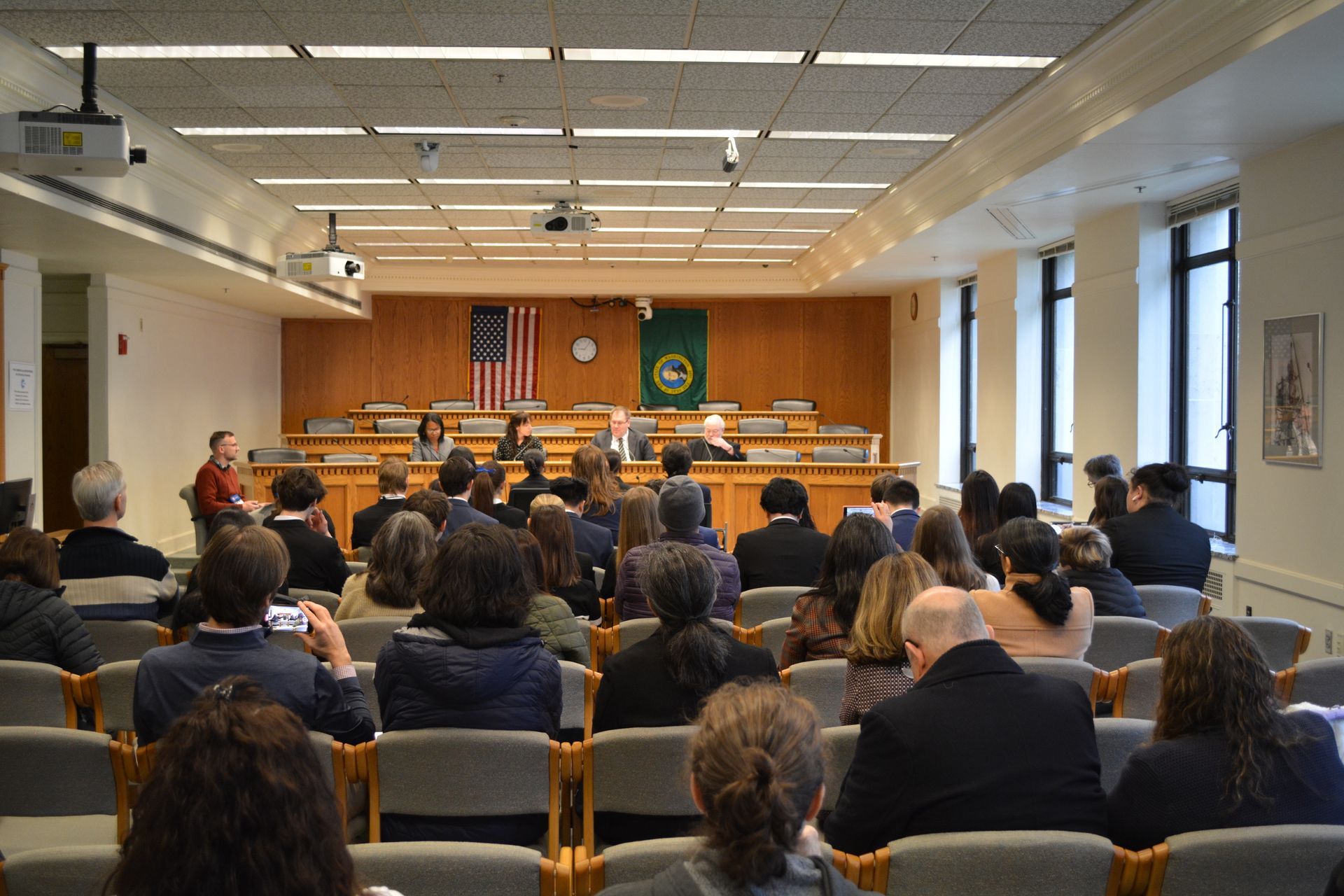 A large group of people are sitting in chairs in a large room.