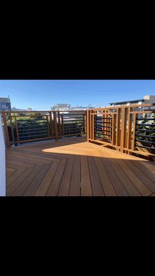A wooden deck with a metal railing and a view of a city.