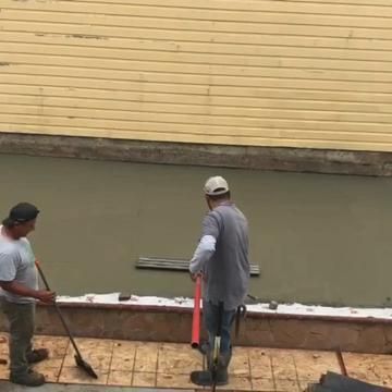 Two men are standing next to each other on a concrete surface.