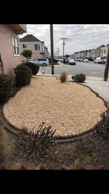 A large pile of gravel is sitting in front of a house.