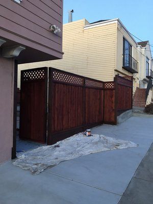A wooden fence is being painted in front of a house.