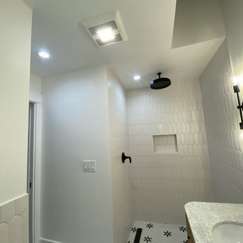 A bathroom with a shower , sink , and ceiling fan.