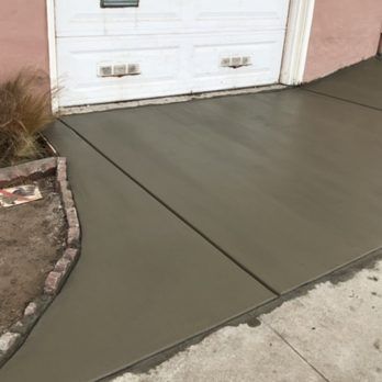 A concrete walkway is being built in front of a garage door.