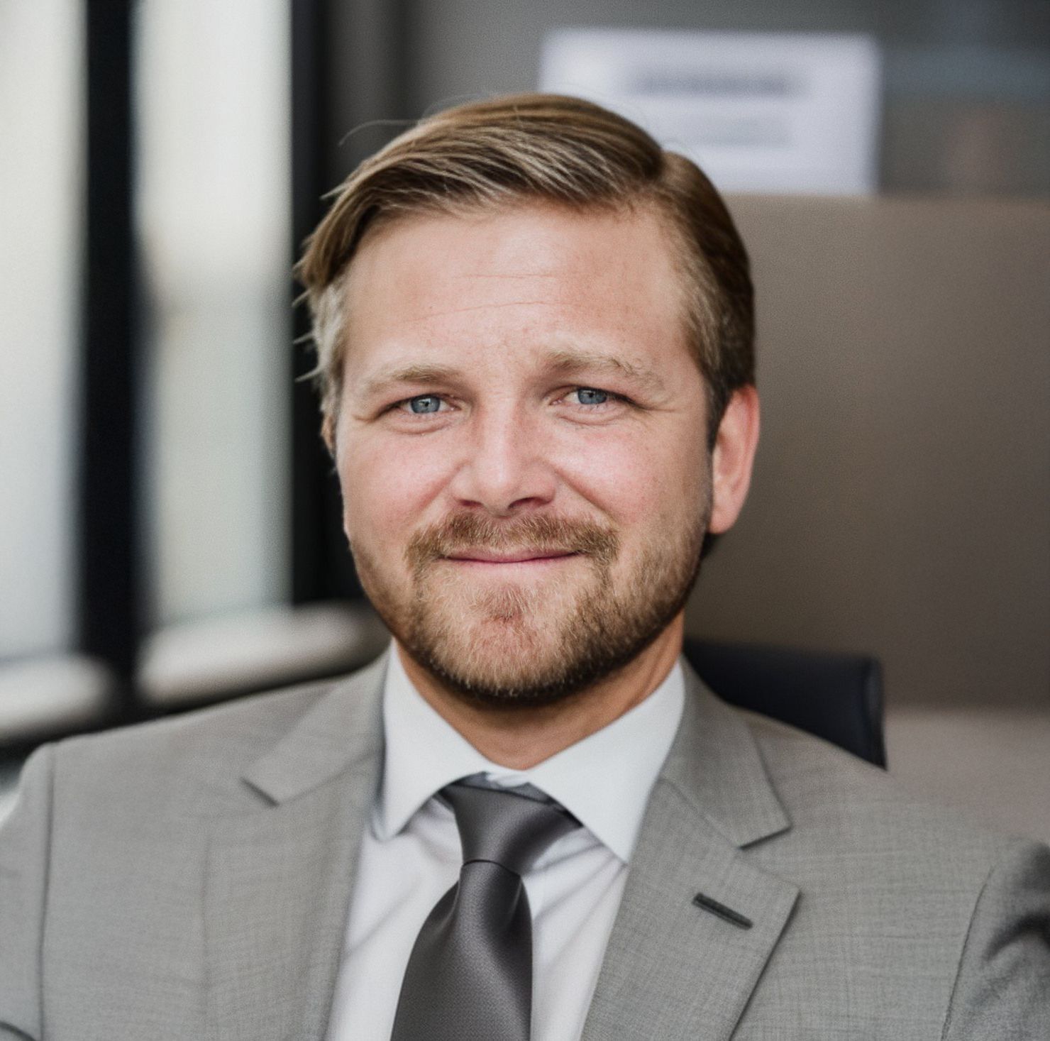 A man in a suit and tie is smiling for the camera