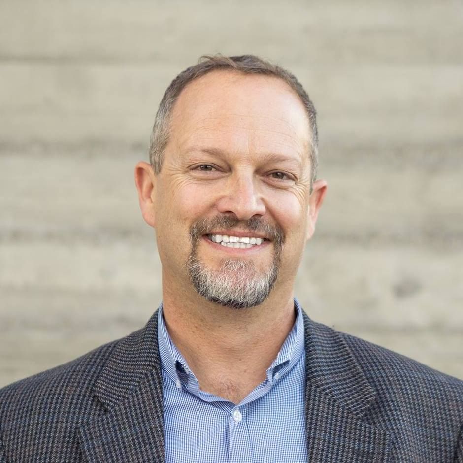 A man with a beard and a suit is smiling for the camera.