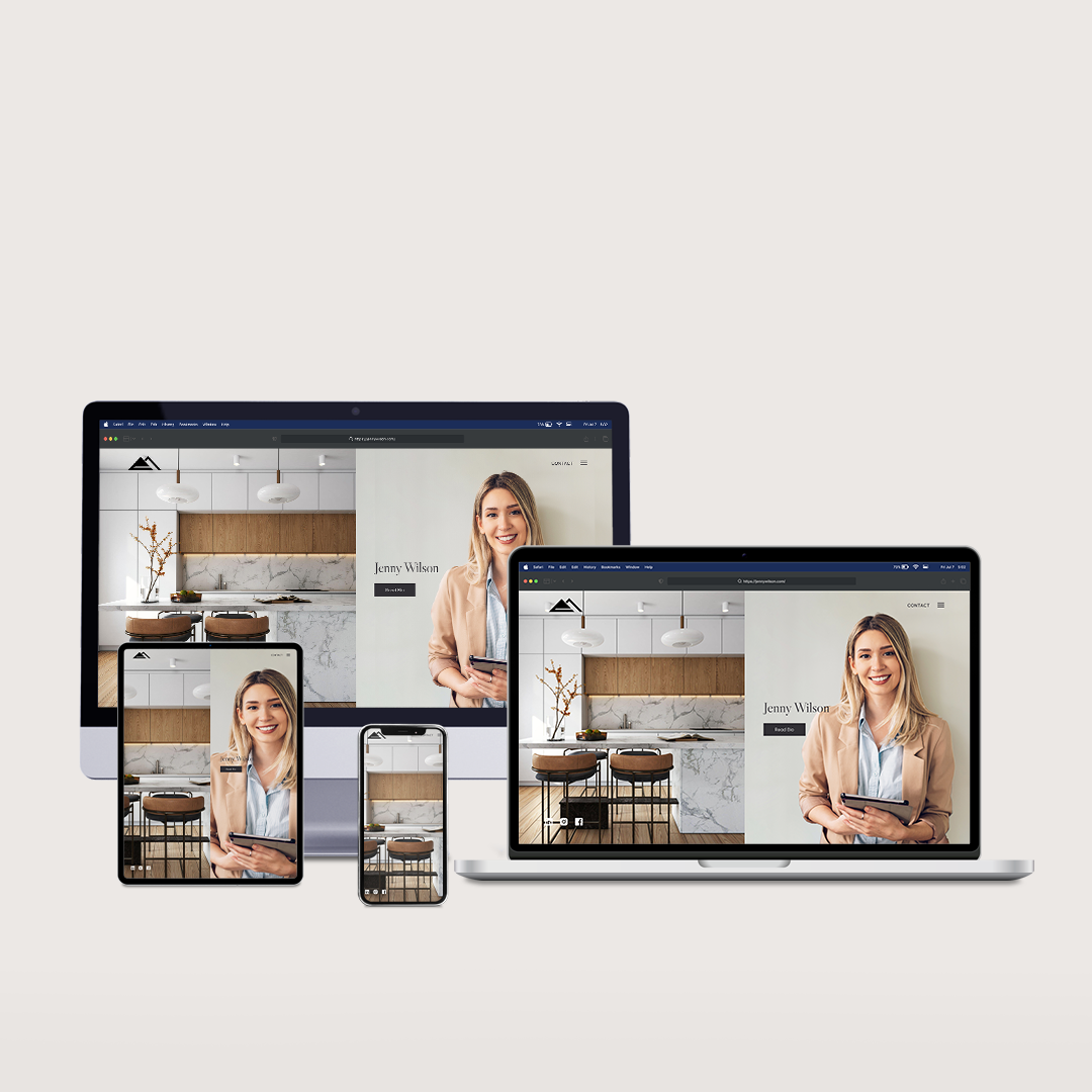 A woman is sitting in a kitchen on a laptop , tablet , and phone.
