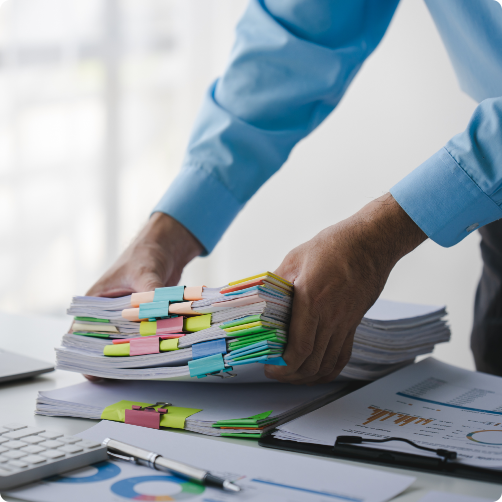 A man is putting a stack of papers on a desk.