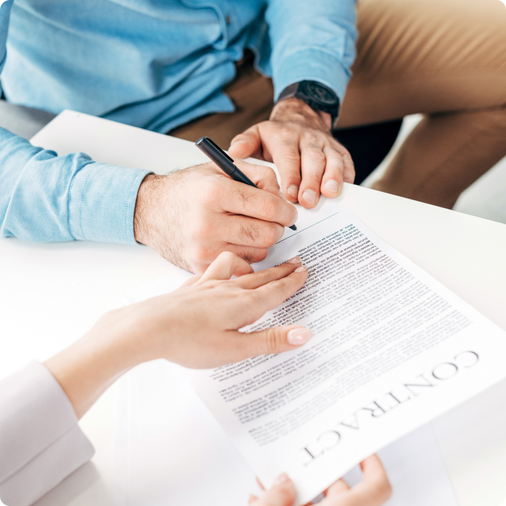 A man and a woman are signing a contract at a table.